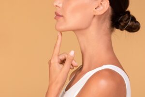 Side profile of a woman touching her chin after getting a chin implant to help improve her face and jawline profile.
