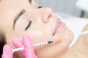 Close-up of a beautiful young woman getting fat transfer injections to fix volume loss in her lower face.